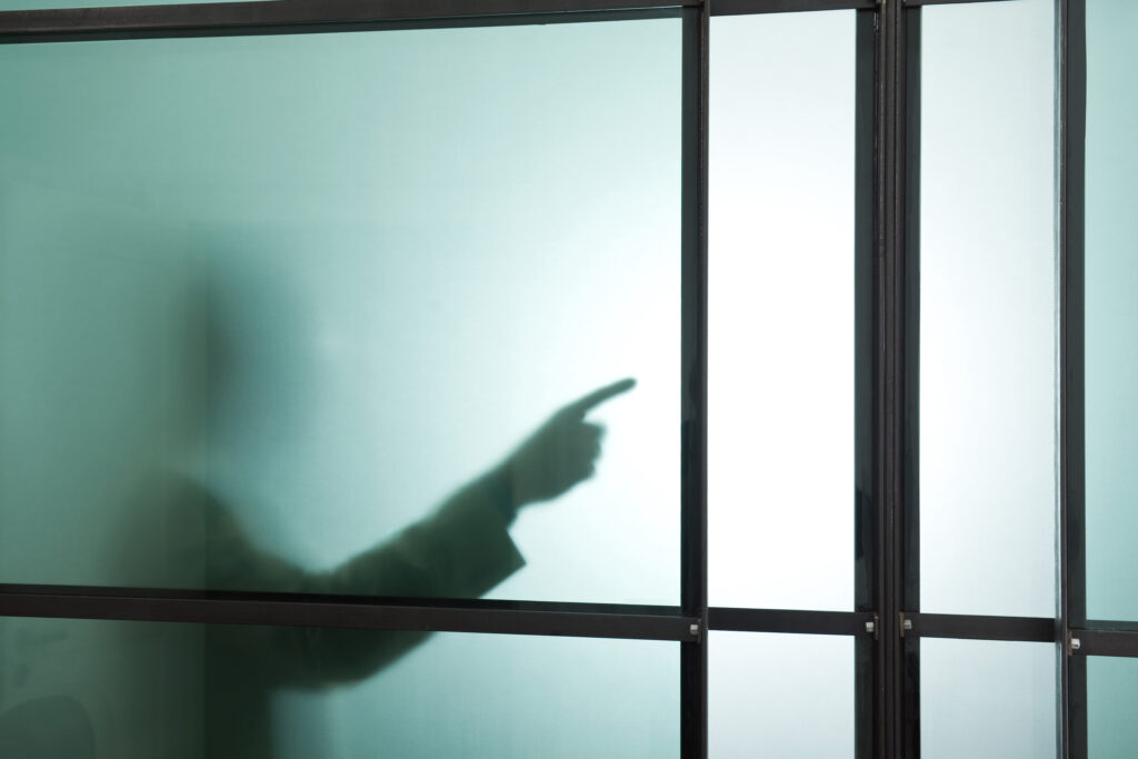 Germany, Munich, Silhouette of businessman behind frosted glass, gesturing